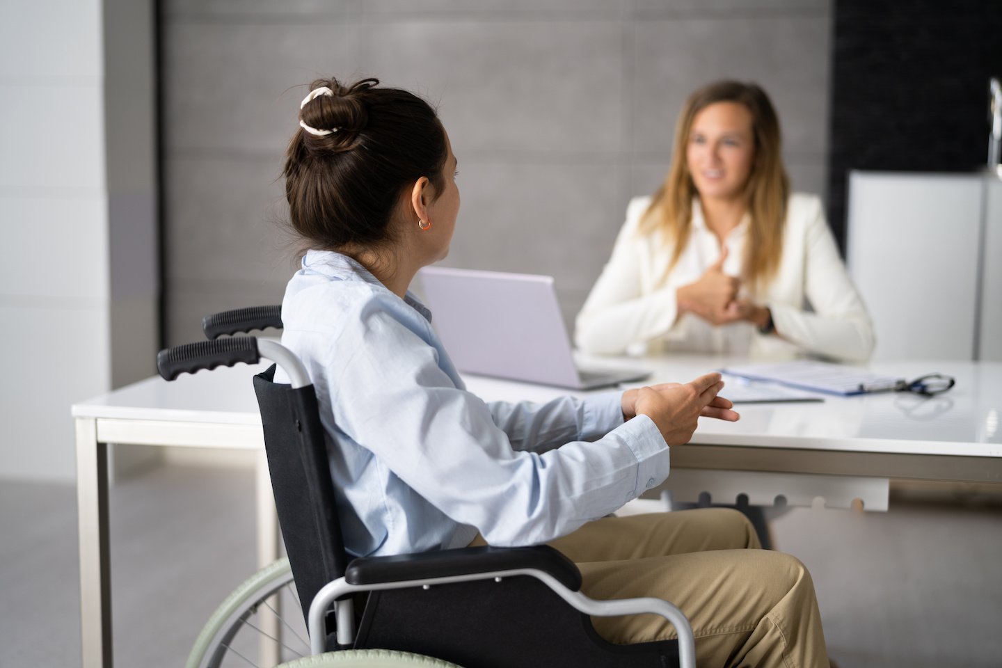 A young women sitting on a wheelchair Learning Sign Language In a Office from sign language tearcher
