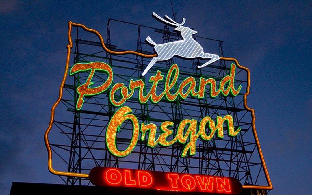 Neon sign that reads Portland Oregon Old Town, on top of a building.